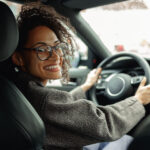 Smiling woman driving a car, looking over her shoulder.