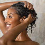 Woman washing her curly hair in the shower.